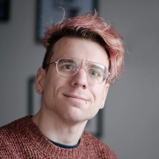 Portrait of Luca; they have pink hair parted to one side, with undercut. They are wearing an hawaiian shirt. Luca Soldaini